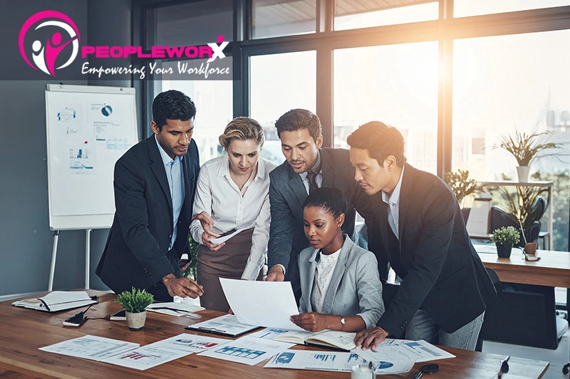 A diverse team gathered around a table reviewing documents