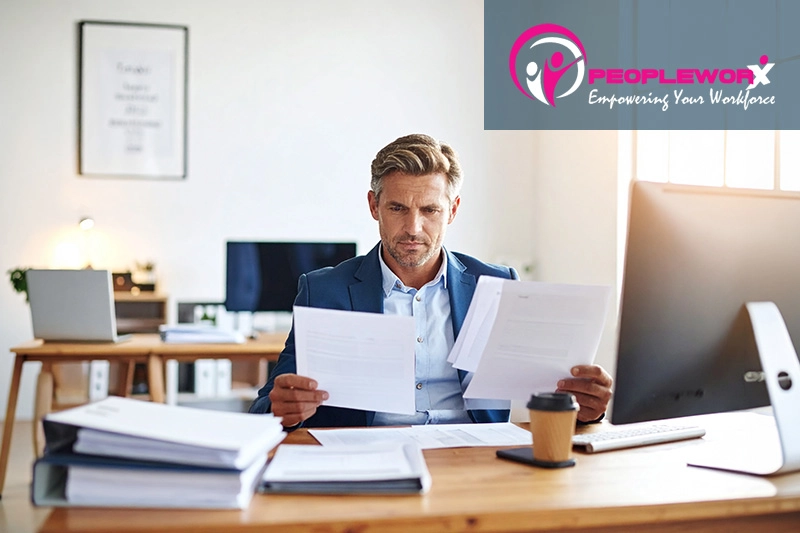 A small business owner or office manager reviewing employee paperwork